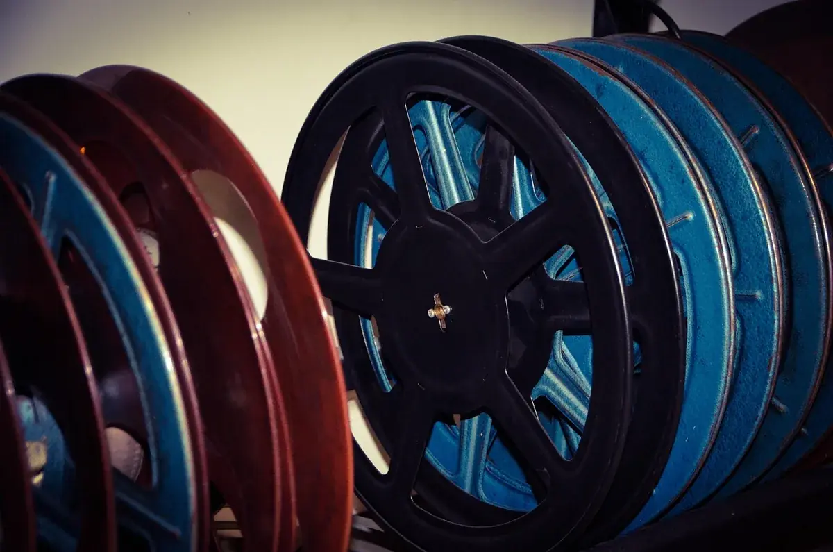 Mehrere Filmspulen mit aufgewickeltem Kinofilm, eine rote und eine blaue, nebeneinander vor dunklem Hintergrund